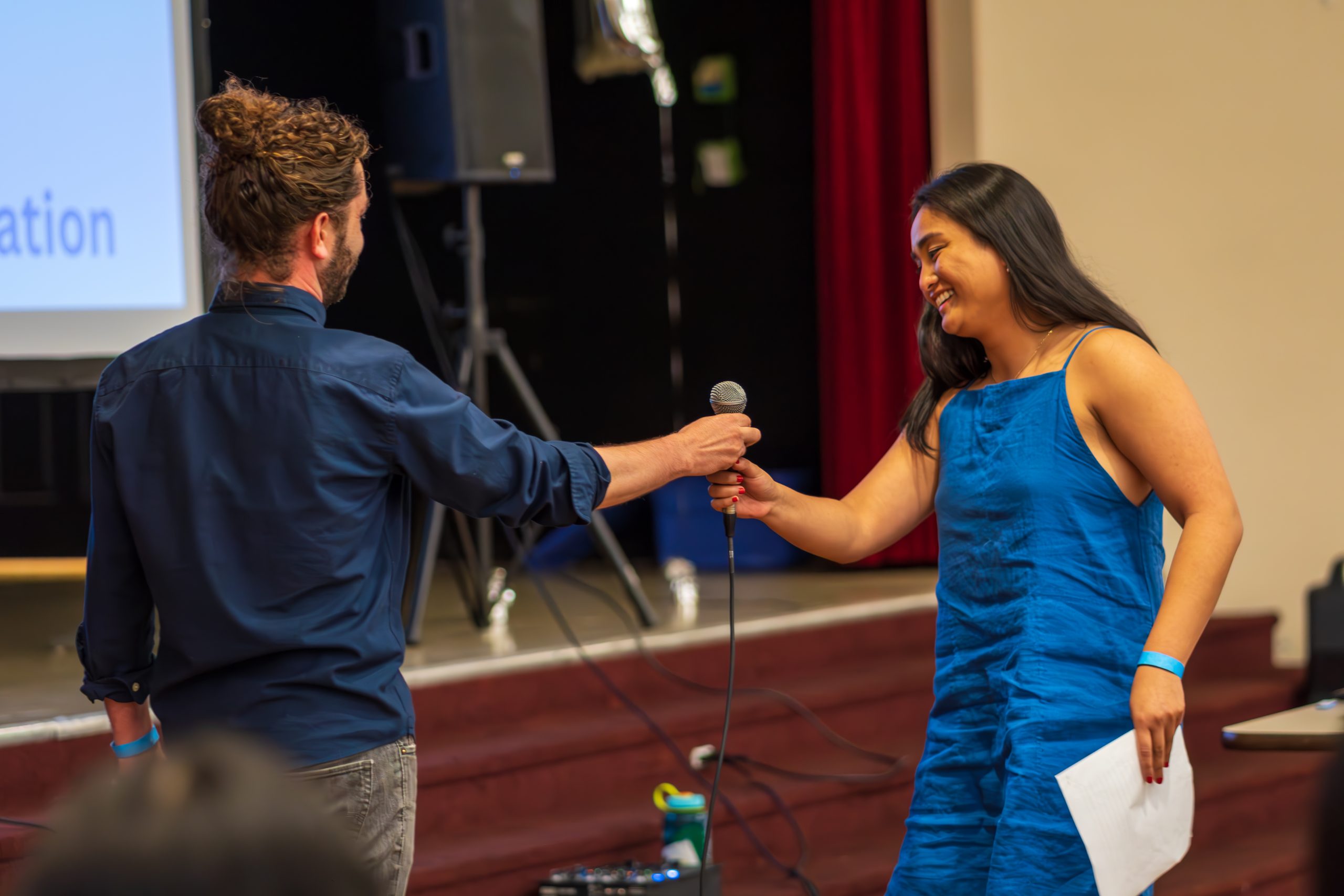 man handing off mic to woman for a speech