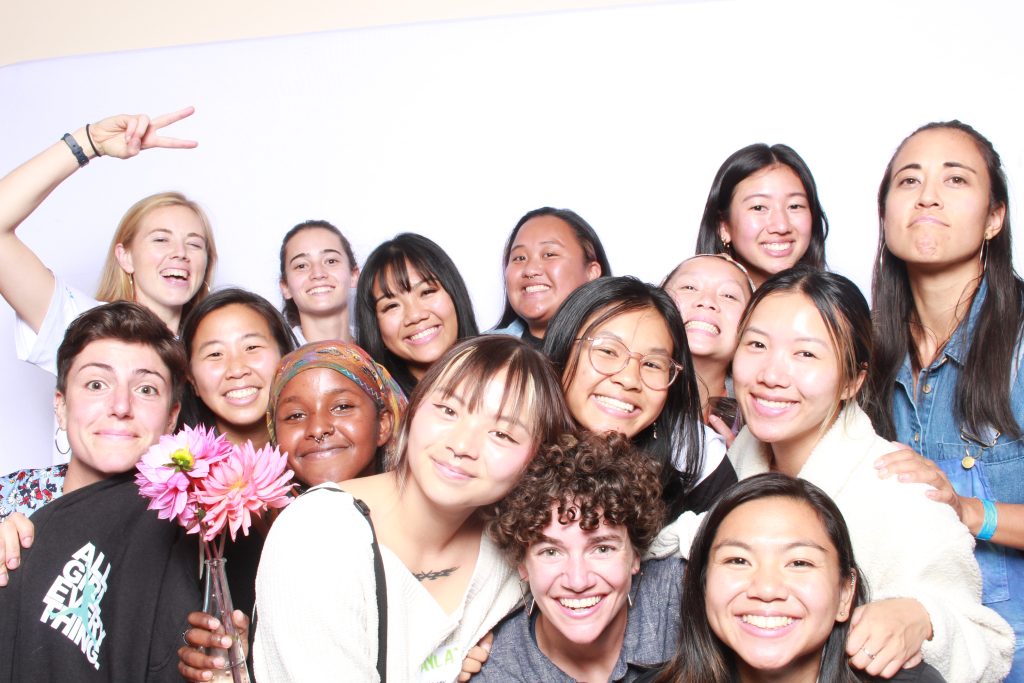 group of bipoc women matching ultimate frisbee players pose in a photobooth with white backdrop
