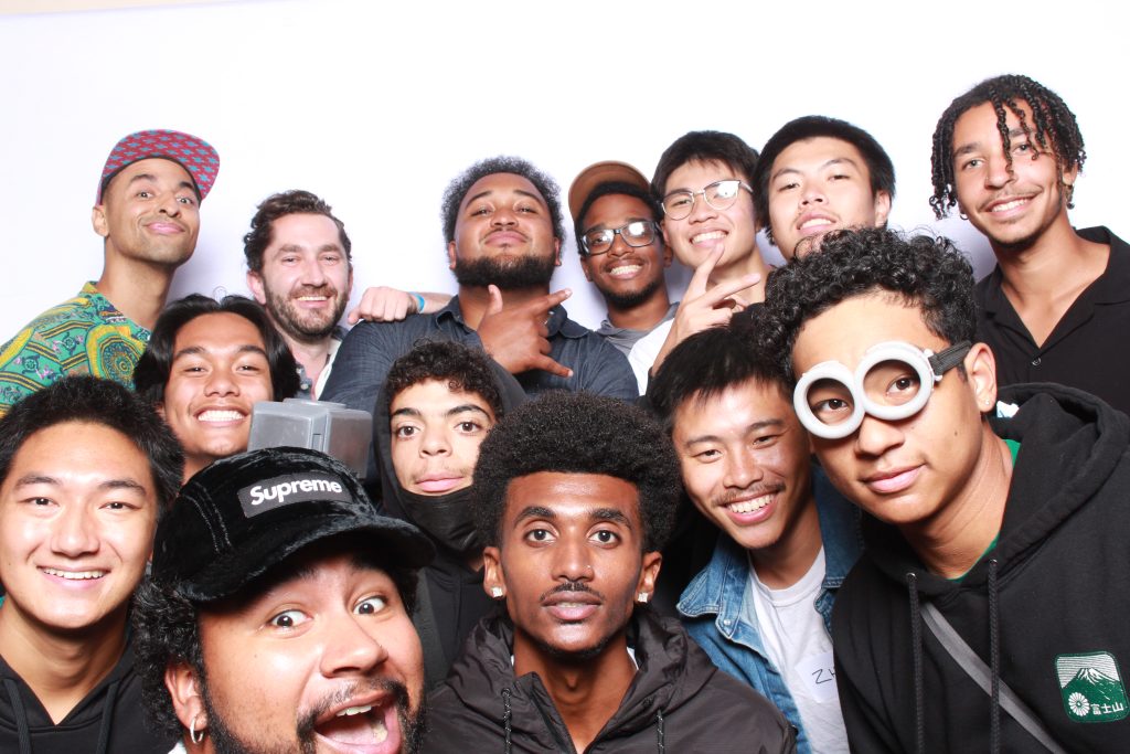 group of young bipoc men matching ultimate players pose in a photobooth with a white backdrop
