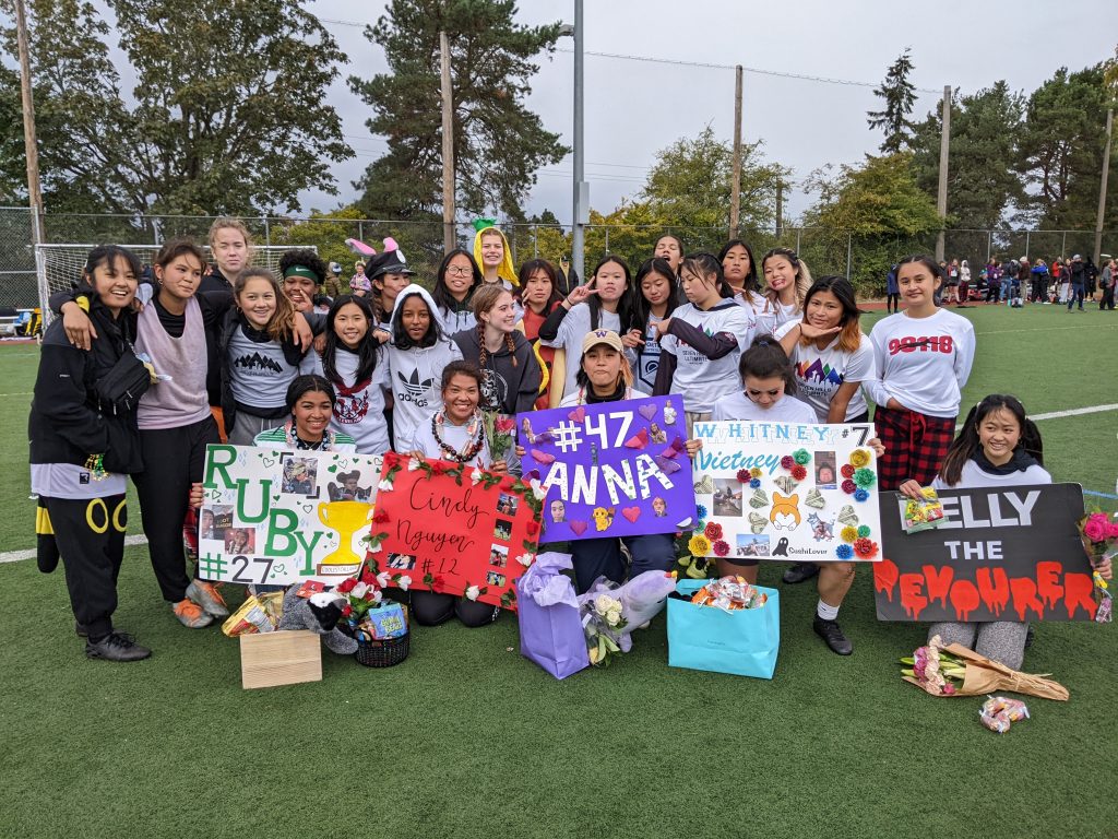 a group of bipoc high school ultimate players celebrate the seniors on their team with signs of each of their names