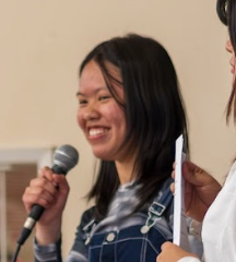 young asian woman speaking in to microphone
